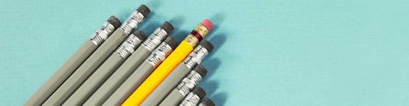 Row of grey pencils with one yellow pencil